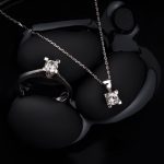 Luxurious silver diamond ring and pendant necklace on a black background, showcasing elegance and sophistication.